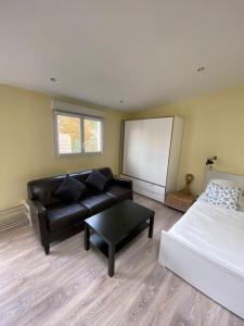 sala de estar con sofá de cuero negro y pizarra en Logement Lumineux - Leuville-sur-Orge en Leuville-sur-Orge