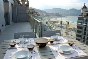 a table with plates and wine glasses on a balcony at Niza La Concha - IB. Apartments in San Sebastián