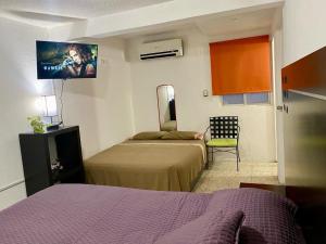 a room with two beds and a tv on the wall at Casa Múkara del Puerto in Veracruz