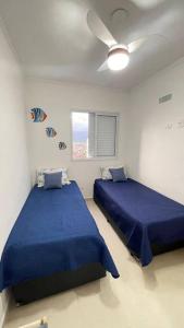 Duas camas num quarto branco com lençóis azuis em Sky116-Apt 2 quartos Caiçara PG em Solemar