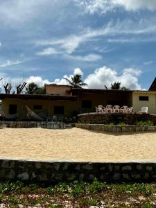 uma praia arenosa com cadeiras e um edifício em Bela vista com pé na areia em Ceará-Mirim