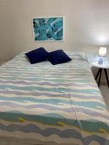 uma cama com almofadas azuis num quarto em Bela vista com pé na areia em Ceará-Mirim