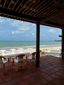 um pátio com uma mesa e cadeiras e a praia em Bela vista com pé na areia em Ceará-Mirim