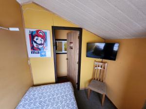 a bedroom with a bed and a chair and a flat screen tv at Hostal Mirador Quellón in Quellón