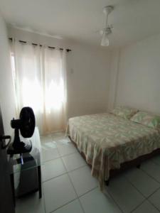 um quarto com uma cama, uma cadeira e uma janela em AP em Ondina em frente a praia em Salvador
