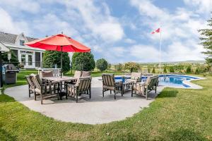 a table and chairs with an umbrella next to a pool at Mountain Ash Farm Country Manor in Creemore