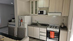 uma cozinha com armários brancos, um fogão e um frigorífico em Complejo Chile Plottier em Plottier