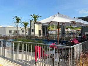 ein Pool mit Sonnenschirm und einigen Stühlen und Anapa in der Unterkunft Apto praia ponta de campina in Cabedelo