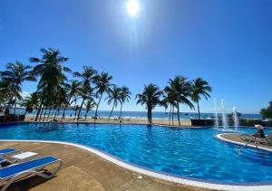 a large swimming pool next to a beach with palm trees at Bahiamar in Pampatar