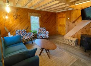a living room with a couch and chairs and a table at Cozy and Charming Cottage with Jacuzzi and Fire Pit! in Livingston Manor