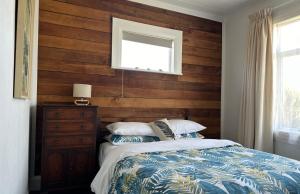 a bedroom with a wooden accent wall and a bed at Kahu's Nest in Hokitika