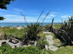 a path to the beach with the ocean in the background at Kahu's Nest in Hokitika