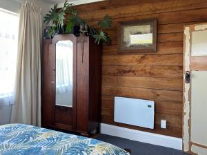 a bedroom with a wooden wall with a bed and a mirror at Kahu's Nest in Hokitika