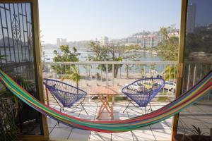 a balcony with chairs and a table and a hammock at Hermoso Departamento Frente Al Mar & Sobre Costera in Acapulco