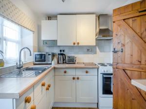 kuchnia z białymi szafkami i drewnianymi drzwiami w obiekcie Buttercup Cottage w mieście Old Buckenham