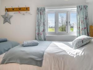 a bedroom with a large white bed and a window at Buttercup Cottage in Old Buckenham