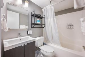 a white bathroom with a sink and a toilet and a tub at Oxford Apartment by At Mine Hospitality in Seattle