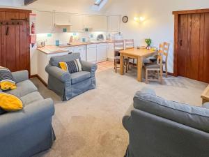a living room with two couches and a kitchen at Woodpecker in Burton Bradstock