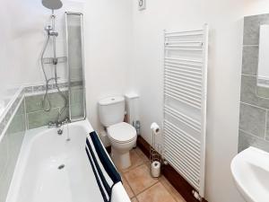 a bathroom with a toilet and a tub and a sink at Woodpecker in Burton Bradstock