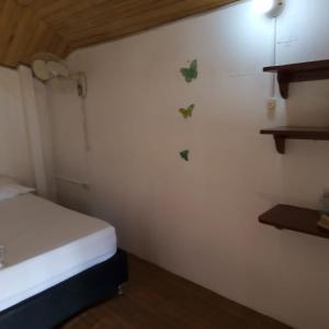 Habitación pequeña con cama y mariposas en la pared en Hostal Paloma Café en Palomino