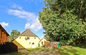 una casa amarilla en un patio con un árbol en 1 Bedroom Gorgeous Apartment In Patzig Auf Rgen, en Patzig