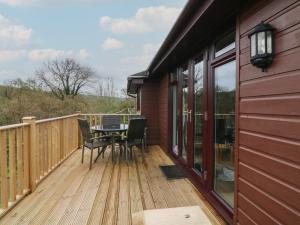 a wooden deck with a table and chairs on it at Chalet Log Cabin C11 in Ilfracombe