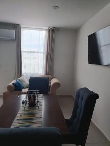 een woonkamer met een tafel en een televisie bij Departamento coto privado con alberca in Mazatlán
