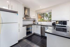 cocina blanca con electrodomésticos blancos y ventana en Spacious and Restful Holiday Home with Backyard en Weetangerra