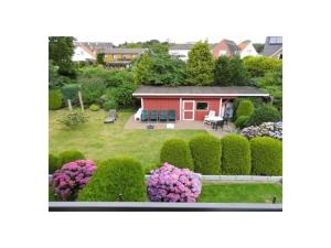 杜能的住宿－LUV and Lee Duhnen Ferienwohnung 3，一座花园,里面设有一座红色的小房子和一些灌木丛