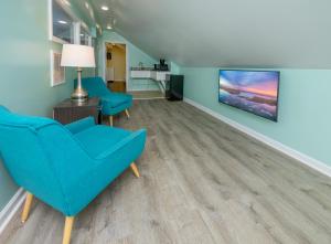 Commander Beach House Hotel في آوشين سيتي: غرفة معيشة مع كراسي زرقاء وتلفزيون بشاشة مسطحة