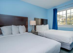 two beds in a room with blue walls and a window at Commander Beach House Hotel in Ocean City