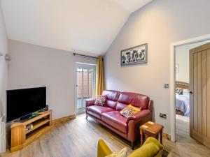 a living room with a red leather couch and a tv at The Loft-uk45061 in Tideswell