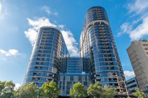 two tall glass buildings against a blue sky at Lovely Sunny 2-bedroom Apartment with Pool and Gym in Phillip