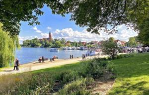 un parc avec des personnes assises sur un banc à côté d'une rivière dans l'établissement Nice Home In Rbel-mritz With Kitchen, à Röbel