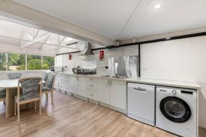 cocina con armarios blancos, mesa y lavadora en Bon Villas B&B Bonville en Coffs Harbour