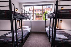 three bunk beds in a room with a window at YHA Hobart Central in Hobart