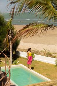 eine Frau, die neben einem Pool neben dem Strand steht in der Unterkunft Villa Mango Beach Houses in Praia de Moitas