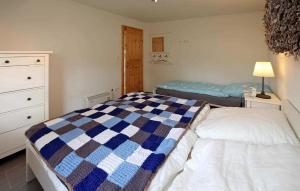 a bedroom with a bed with a blue and white quilt at 1 Bedroom Nice Home In Kummerow in Kummerow