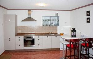 a kitchen with white cabinets and a table with red chairs at Lovely Apartment In Sommersdorf With Wifi in Sommersdorf