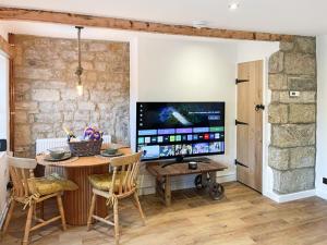 a dining room with a table and a large screen television at Middle Cottage in Middlesmoor