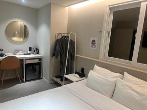 a bedroom with a bed and a desk and a mirror at Hotel Yam in Busan