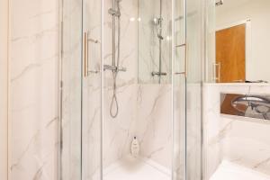 een douche met een glazen deur in de badkamer bij Wild Roses Serviced Apartments - Angel in Londen