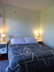 1 dormitorio con 1 cama con edredón azul y 2 lámparas en Casa Florida, en Villa Serrana
