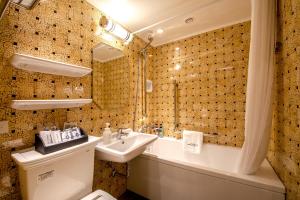 uma casa de banho com um lavatório, um WC e uma banheira em Hotel Monterey Okinawa Spa & Resort em Onna
