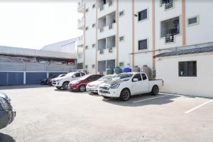 un gruppo di auto parcheggiate in un parcheggio di fronte a un edificio di Boss Way แมนชั่น a Ban Pak Khlong Si