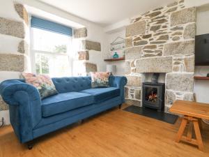 a blue couch in a living room with a fireplace at Kilden Cottage in Helston