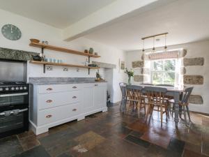 a kitchen with a table and chairs and a stove at Kilden Cottage in Helston