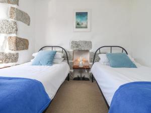 ヘルストンにあるKilden Cottageの白い壁の客室で、ベッド2台、青い枕が備わります。