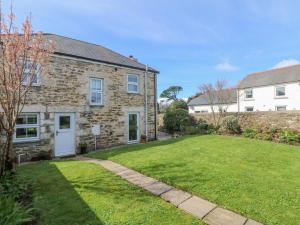 a brick house with a lawn in front of it at Kilden Cottage in Helston