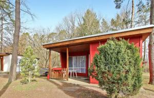 a red cabin in the woods with a tree at Fh Rot in Warenthin